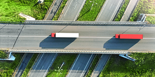 Aerial view of two shipping trucks driving down a highway